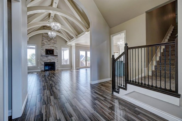 foyer entrance featuring a chandelier, a wealth of natural light, dark wood-type flooring, and a fireplace