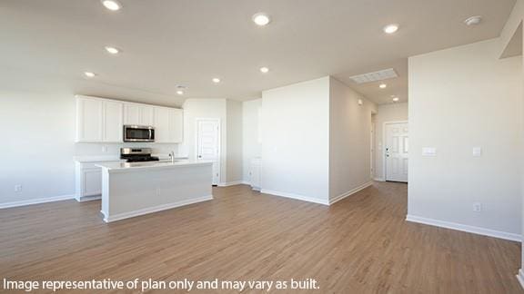 kitchen with range, white cabinetry, stainless steel microwave, and open floor plan