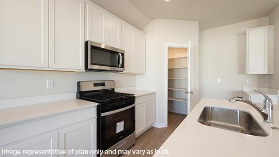 kitchen featuring white cabinets, stainless steel appliances, light countertops, light wood-type flooring, and a sink