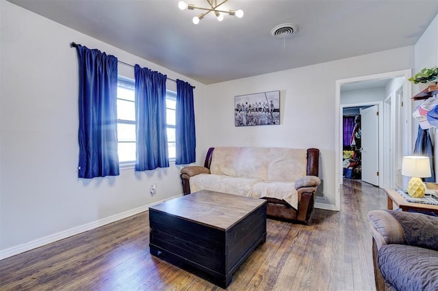 living room with visible vents, an inviting chandelier, baseboards, and wood finished floors