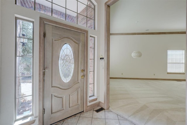 foyer entrance featuring light carpet, visible vents, baseboards, and light tile patterned floors