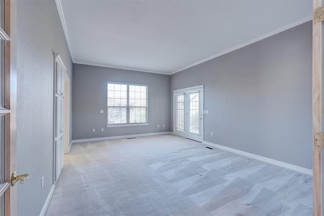 spare room with baseboards, crown molding, and light colored carpet