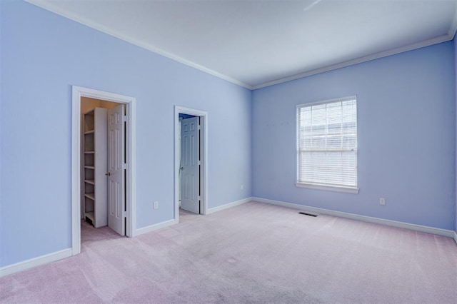 carpeted spare room with baseboards, visible vents, and crown molding