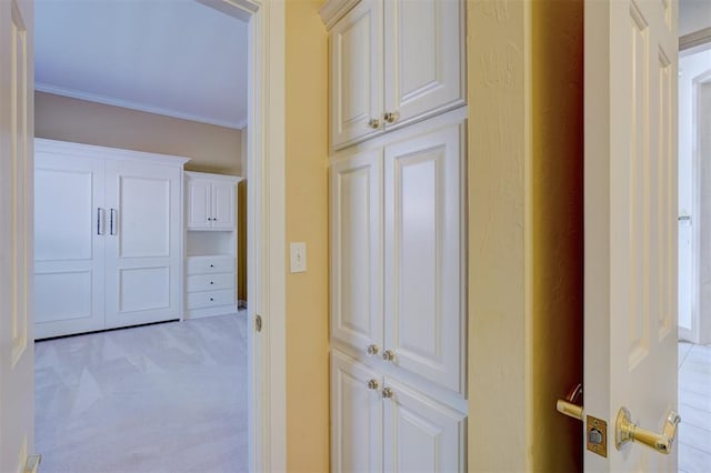 hallway with ornamental molding and light colored carpet