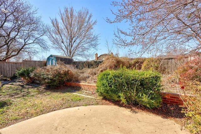 view of yard with a fenced backyard, an outdoor structure, and a patio