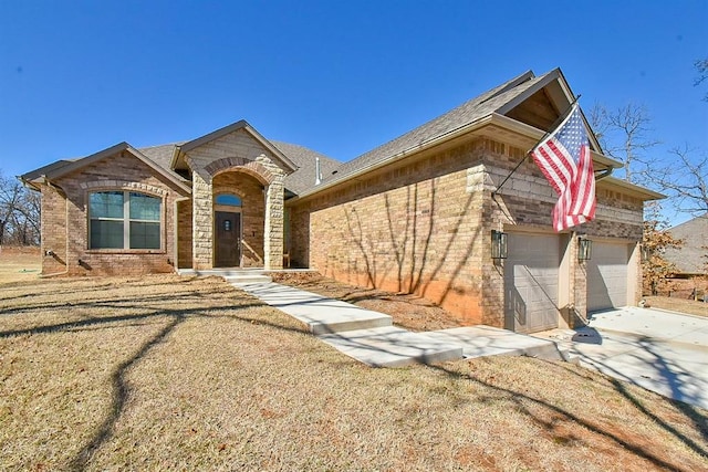 view of front of property featuring brick siding, a shingled roof, concrete driveway, a garage, and stone siding