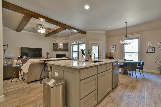 kitchen with beam ceiling, a sink, light wood-style flooring, and light stone countertops