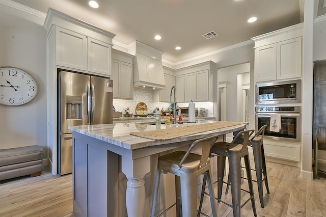 kitchen with tasteful backsplash, visible vents, appliances with stainless steel finishes, light stone countertops, and custom exhaust hood