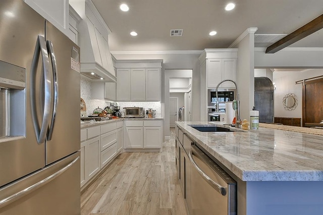 kitchen with light stone counters, light wood-style flooring, visible vents, appliances with stainless steel finishes, and backsplash