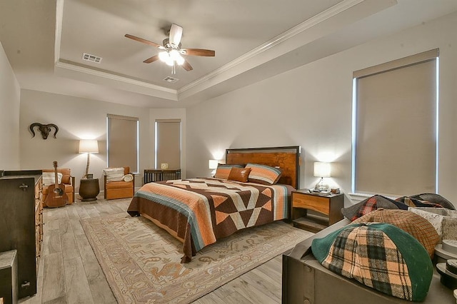 bedroom with visible vents, crown molding, a tray ceiling, and wood finished floors