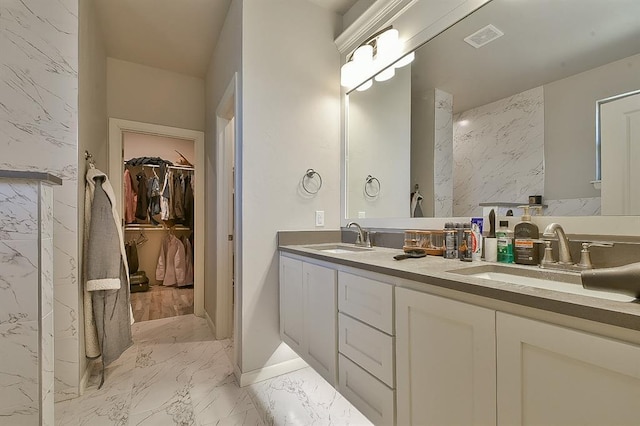 bathroom with marble finish floor, a sink, visible vents, and a walk in closet