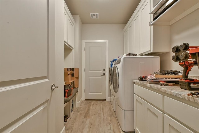 laundry area featuring washer and clothes dryer, light wood-type flooring, cabinet space, and visible vents