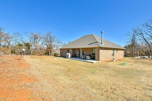 rear view of property with brick siding, a lawn, and a patio