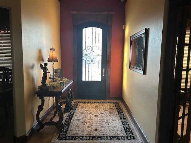 foyer entrance with a textured wall and baseboards