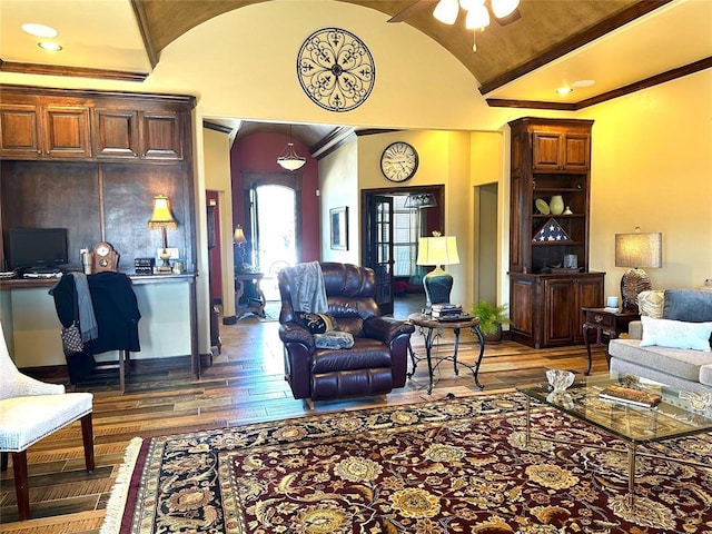 living room featuring baseboards, a ceiling fan, hardwood / wood-style flooring, ornamental molding, and vaulted ceiling