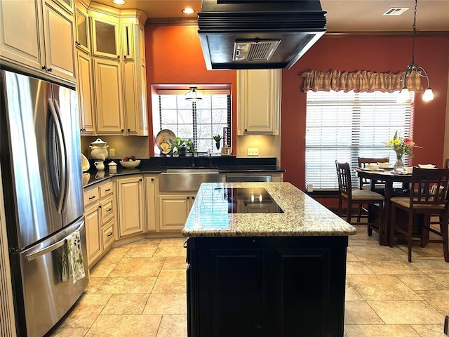 kitchen with visible vents, freestanding refrigerator, a kitchen island, a sink, and exhaust hood