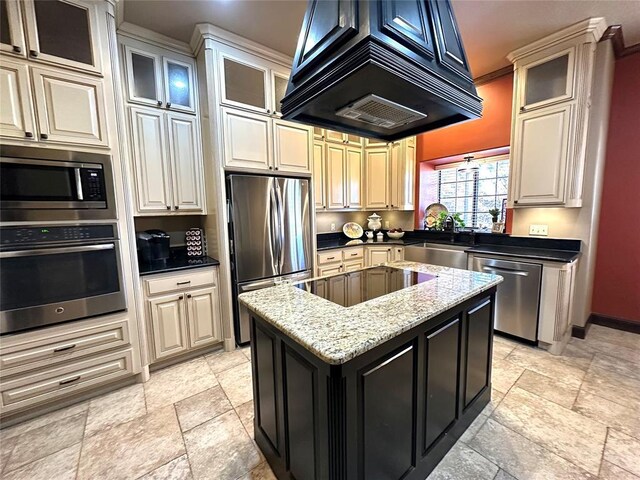 kitchen with stone tile floors, stainless steel appliances, a sink, a kitchen island, and ventilation hood