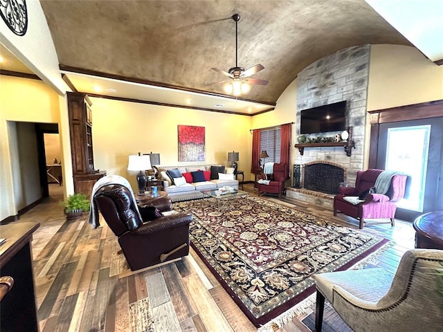 living area featuring lofted ceiling, a fireplace, a ceiling fan, baseboards, and hardwood / wood-style floors