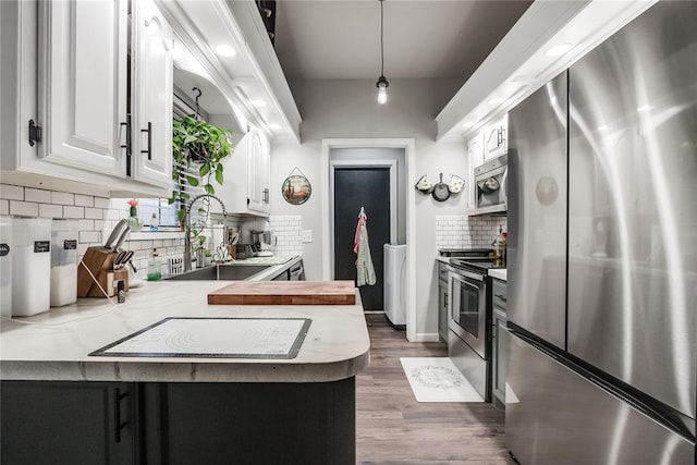 kitchen featuring stainless steel appliances, light countertops, white cabinetry, a sink, and a peninsula