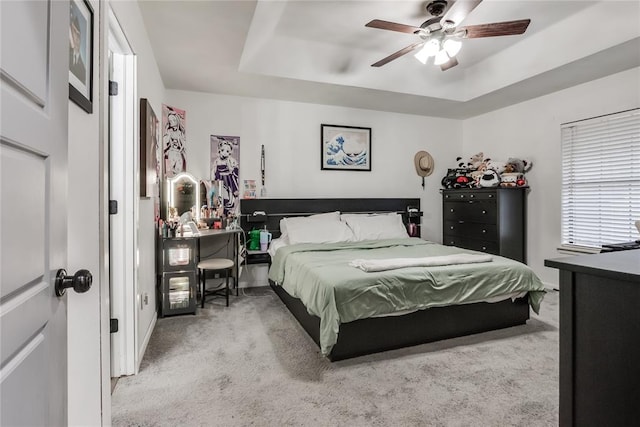 bedroom with ceiling fan, carpet floors, and a raised ceiling