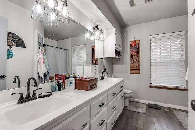 bathroom featuring baseboards, visible vents, a sink, and wood finished floors