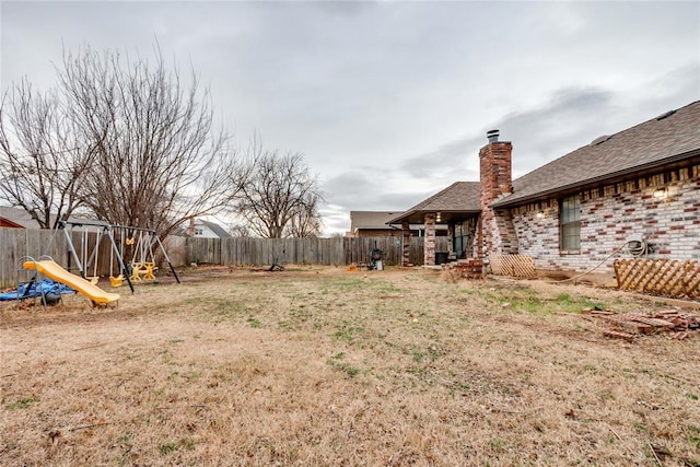 view of yard with a fenced backyard and a playground