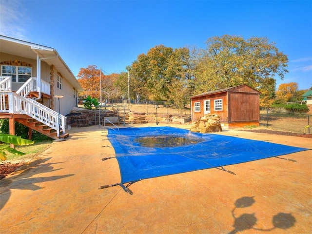 view of pool with a fenced in pool, an outbuilding, a patio, stairway, and fence