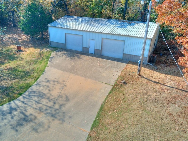 exterior space featuring an outbuilding, metal roof, a detached garage, and central air condition unit