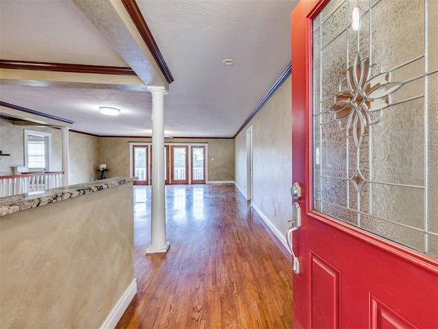 entryway featuring baseboards, crown molding, ornate columns, and wood finished floors