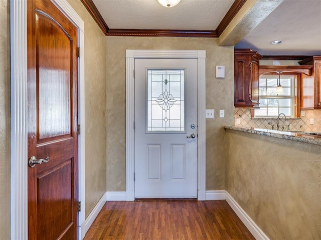 doorway with dark wood-style floors, baseboards, and crown molding