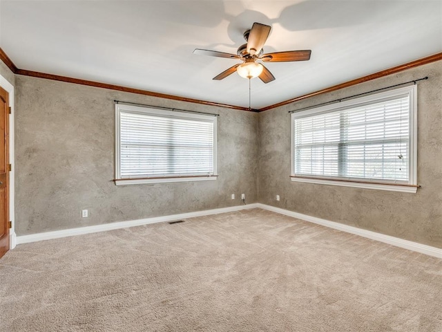 unfurnished room with a ceiling fan, baseboards, visible vents, carpet, and crown molding