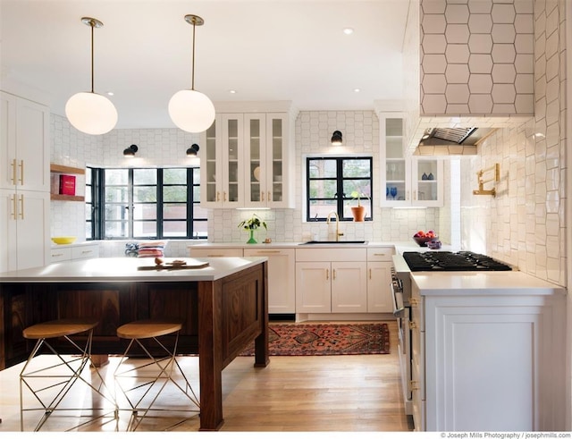 kitchen featuring stainless steel stove, a sink, decorative backsplash, light countertops, and recessed lighting