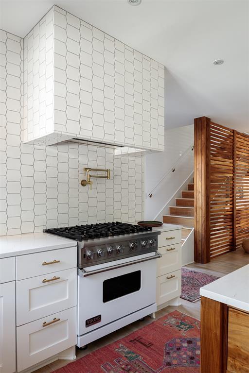 kitchen featuring high end white range, backsplash, white cabinets, light countertops, and recessed lighting