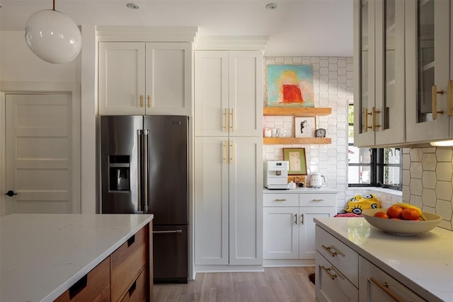 kitchen featuring high quality fridge, open shelves, backsplash, light wood-style floors, and light stone counters