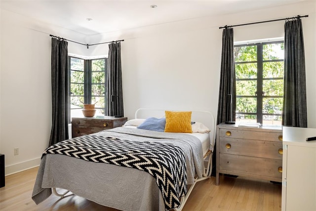 bedroom featuring light wood-style flooring, multiple windows, and baseboards