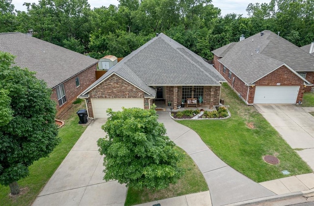 view of front facade with concrete driveway, a shingled roof, an attached garage, and a front yard