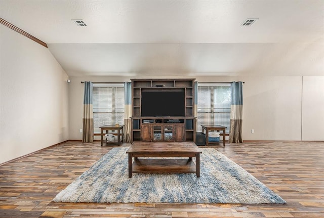 living area with baseboards, visible vents, vaulted ceiling, and wood finished floors