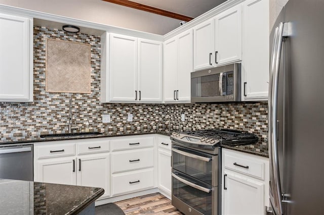 kitchen with appliances with stainless steel finishes, a sink, backsplash, and light wood finished floors