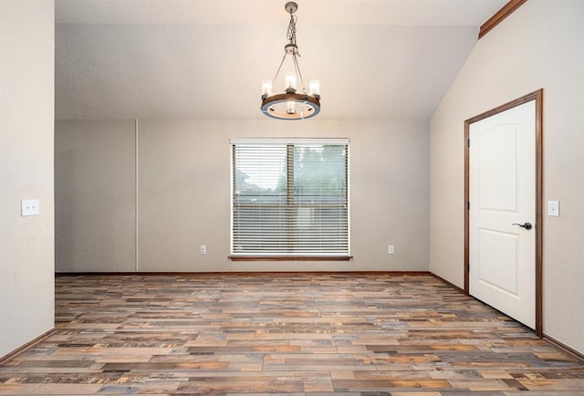 spare room with lofted ceiling, a chandelier, and wood finished floors