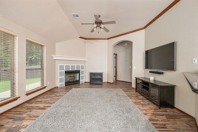 living area featuring visible vents, lofted ceiling, ceiling fan, ornamental molding, and wood finished floors