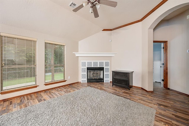 unfurnished living room featuring visible vents, arched walkways, wood finished floors, vaulted ceiling, and a fireplace