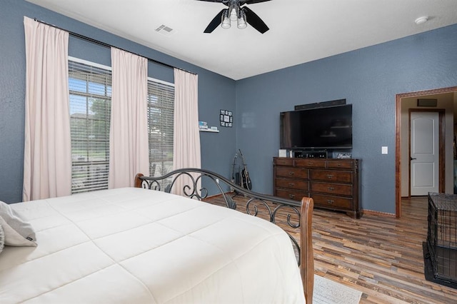 bedroom with baseboards, wood finished floors, visible vents, and a ceiling fan