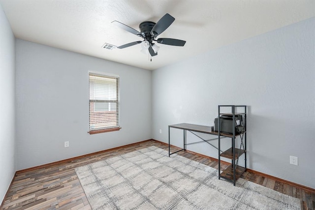 unfurnished office featuring a ceiling fan, baseboards, visible vents, and wood finished floors