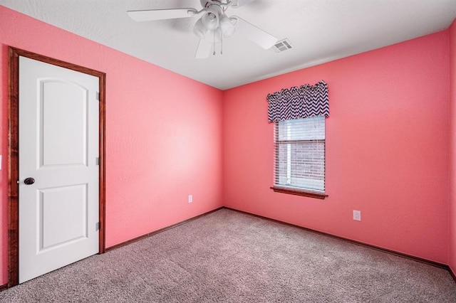 empty room with carpet floors, visible vents, and a ceiling fan