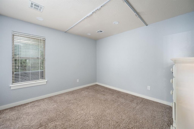 carpeted spare room featuring baseboards and visible vents