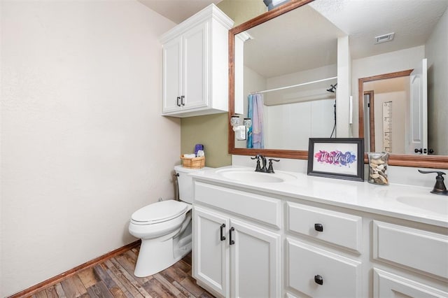 bathroom with toilet, visible vents, a sink, and wood finished floors