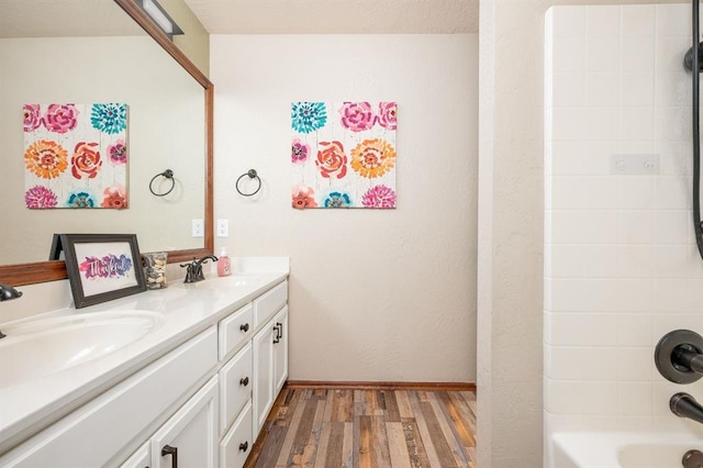 full bathroom with double vanity, baseboards, a sink, and wood finished floors