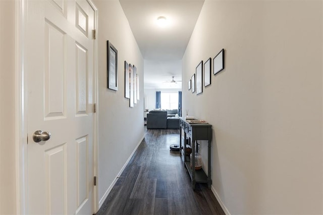 hallway featuring dark wood-style flooring and baseboards