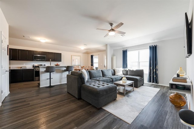 living room featuring dark wood-style floors, ceiling fan, visible vents, and baseboards