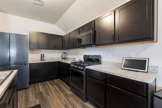 kitchen featuring visible vents, dark wood finished floors, lofted ceiling, stainless steel appliances, and dark brown cabinets